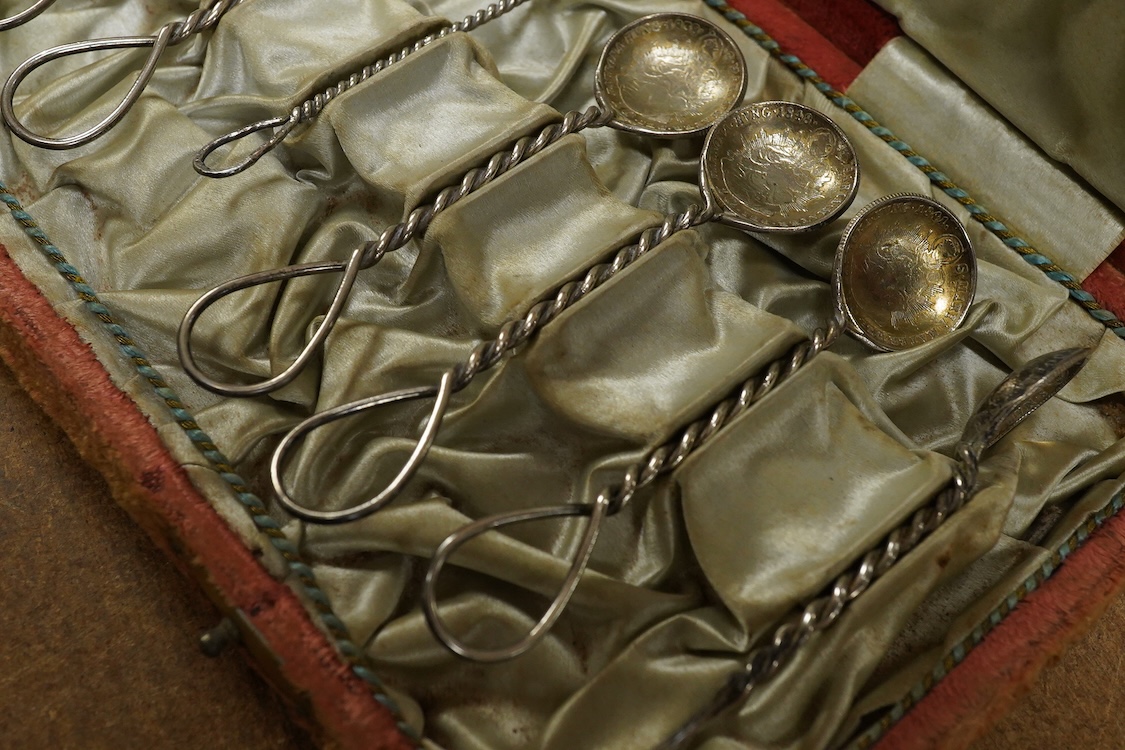 A cased set of twelve assorted white metal coffee spoons, with spiral stems and coin bowls.